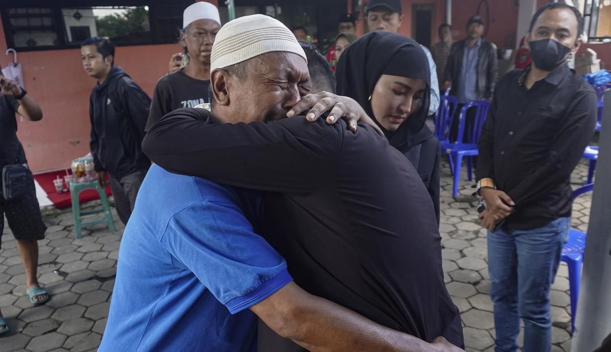 Di tempat lain, Presiden Arema FC, Gilang Widya Pramana (tengah) memeluk kerabat dari salah satu korban lainnya, Iwan Junaedi saat bertakziah ke tempat tinggal korban. (AP/Dicky Bisinglasi)