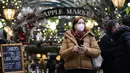 Seorang wanita memakai masker saat dia berjalan di pasar Covent Garden, di London, Kamis (16/12/2021). Inggris mencatat jumlah tertinggi infeksi COVID-19 baru yang dikonfirmasi pada hari Rabu (15/12) sejak pandemi dimulai. (AP Photo/Alberto Pezzali)