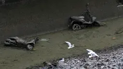 Sejumlah burung camar terbang di atas bangkai skuter di Kanal Saint Martin, Paris selama proses pengeringan dan pembersihan. (05/1/2016) (AFP PHOTO / PATRICK KOVARIK)