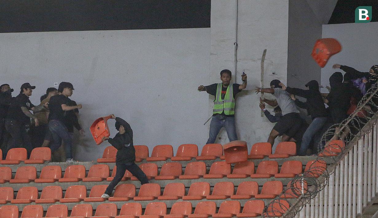 Sejumlah pendukung Persib Bandung (kiri) dan pendukung Persis Solo bersitengan saat pertandingan pekan ke-32 BRI Liga 1 2022/2023 antara Persib Bandung melawan Persis Solo yang berlangsung di Stadion Pakansari, Bogor, Selasa (04/04/2023). (Bola.com/Bagaskara Lazuardi)