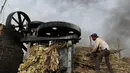 Seorang pria bekerja di pabrik jaggery di pinggiran Bareilly, India, Selasa (23/3/2021).  Jaggery adalah gula tradisional yang tidak dimurnikan yang dikonsumsi di banyak bagian Asia, terbuat dari molase tebu dan nira kurma. (AP Photo/Rajesh Kumar Singh)