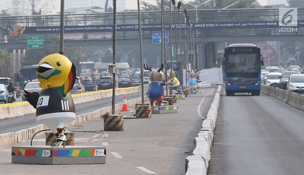 Bus Transjakarta melintas di samping patung maskot Asian Games 2018 yang menghiasi Jalan Sudirman, Jakarta, Rabu (8/8). Pemasangan maskot tersebut untuk menyemarakan Asian Games 2018 yang akan dibuka 18 Agustus 2018. (Liputan6.com/Immanuel Antonius)