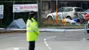 Petugas berdiri di dekat lokasi jatuhnya jet Hawker Hunter di Jalan Raya A27, Shoreham, Inggris, Minggu (23/8/2015). Pesawat yang tengah mengikuti Shoreham Airshow tersebut menabrak sejumlah mobil dan menewaskan  tujuh orang. (REUTERS/Luke MacGregor)