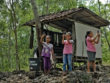 Siswa sekolah dasar mencari sinyal internet sebelum mengikuti pembelajaran secara online menggunakan smartphone di bukit Temulawak, Yogyakarta, Jumat (8/5/2020). Mereka harus ke atas bukit untuk mendapat sinyal yang bagus agar kegiatan belajar secara online dapat berlangsung. (AGUNG SUPRIYANTO/AFP)
