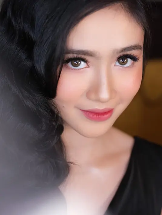 Menggelung rambut panjangnya ke samping, Febby mengenakan pakaian berwarna hitam sambil menatap penuh kecantikan. (Instagram/febbyrastanty)