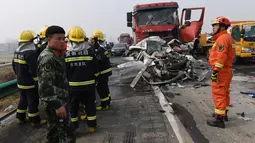 Petugas pemadam kebakaran dikerahkan ke lokasi kecelakaan beruntun 30 kendaraan di jalan raya dekat Yingshang, China timur, Rabu (15/11). Tak hanya mobil penumpang ukuran sedang saja yang terbakar hangus melainkan juga beberapa unit truk. (STR / AFP)