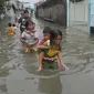 Sejumlah anak menggendong adiknya melewati banjir di Rawa Buaya, Jakarta, Minggu (28/2/2016). Banjir akibat luapan Kali Mookervart ini menyebabkan ratusan rumah warga tergenang air rata-rata satu meter. (Liputan6.com/Gempur M Surya)