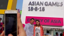 Sepasang warga di foto dengan latar layar Countdown Asian Games 2018 saat Car Free Day di Bundaran HI, Jakarta, Minggu, (10/09). Hitung mundur tersebut telah memasuki H - 342. (Liputan6.com/Fery Pradolo)