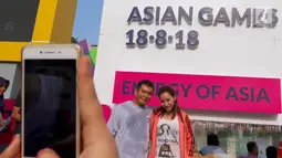 Sepasang warga di foto dengan latar layar Countdown Asian Games 2018 saat Car Free Day di Bundaran HI, Jakarta, Minggu, (10/09). Hitung mundur tersebut telah memasuki H - 342. (Liputan6.com/Fery Pradolo)