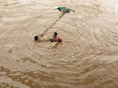 Anak-anak berenang di aliran Sungai Ciliwung yang meluap di Rawajati, Jakarta, Selasa (6/2). Meluapnya Sungai Ciliwung akibat intensitas hujan yang tinggi. (Liputan6.com/Immanuel Antonius)