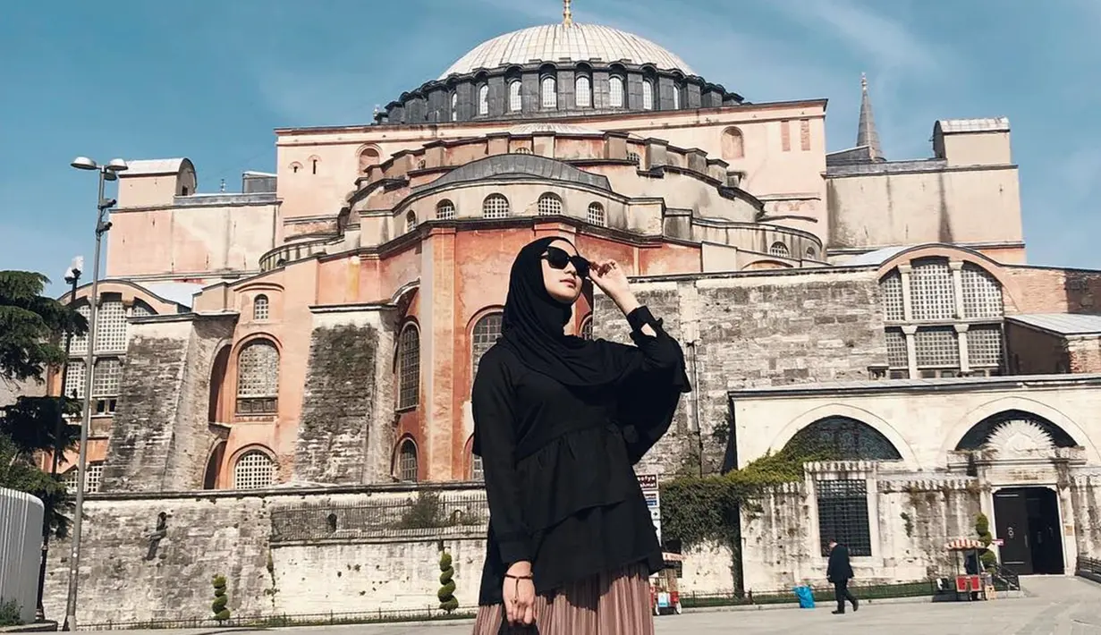 Potret cantik Citra Kirana kenakan hijab dan atasan warna hitam dengan kacamatanya, berada di depan Hagia Sophia, yang dahulunya Katedral, Masjid dan kini jadi museum di Istanbul, Turki. (Liputan6.com/IG/@citraciki)