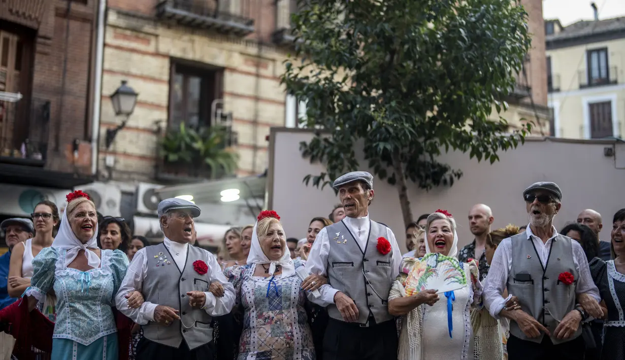 Orang-orang yang mengenakan pakaian tradisional 'chulapo' menari selama perayaan San Cayetano, santo pelindung tenaga kerja dan roti, di lingkungan Lavapies di Madrid, Spanyol, Sabtu (6/8/2022). Festival San Cayetano menandai awal dari serangkaian festival populer di Madrid. (AP Photo/Manu Fernandez)