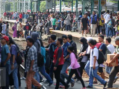 Sejumlah penumpang Comuter Line menyebrang antar peron di Stasiun Manggarai, Jakarta, Selasa (28/3). Stasiun Manggarai dipadati penumpang yang hendak berlibur pada Hari Raya Nyepi Tahun Baru Saka 1939. (Liputan6.com/Faizal Fanani)
