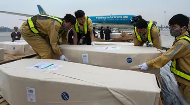 Petugas memasukkan peti mati berisi jenazah yang ditemukan tewas dalam truk kontainer di Inggris ke dalam ambulans setibanya di bandara internasional Noi Bai, Hanoi, Rabu (27/11/2019). Sebanyak 16 dari 39 jenazah telah tiba di Vietnam untuk dibawa ke kampung halaman masing-masing. (Nhac NGUYEN/AFP)