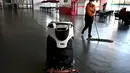 Robot dan seorang karyawan membersihkan lantai Pusat Media Utama selama Olimpiade Musim Dingin Beijing 2022 pada 5 Februari 2022. (AFP/Gabriel Bouys)
