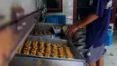 Pekerja memasukkan adonan kue ke oven di industri pembuatan kue kering Pusaka Kwitang, Jakarta, Kamis (30/4/2020). Kue kering yang dijual seharga Rp480 ribu per kaleng itu pada bulan Ramadan tahun ini mengalami penurunan produksi hingga 500 kaleng akibat pandemi COVID-19. (Liputan6.com/Johan Tallo)