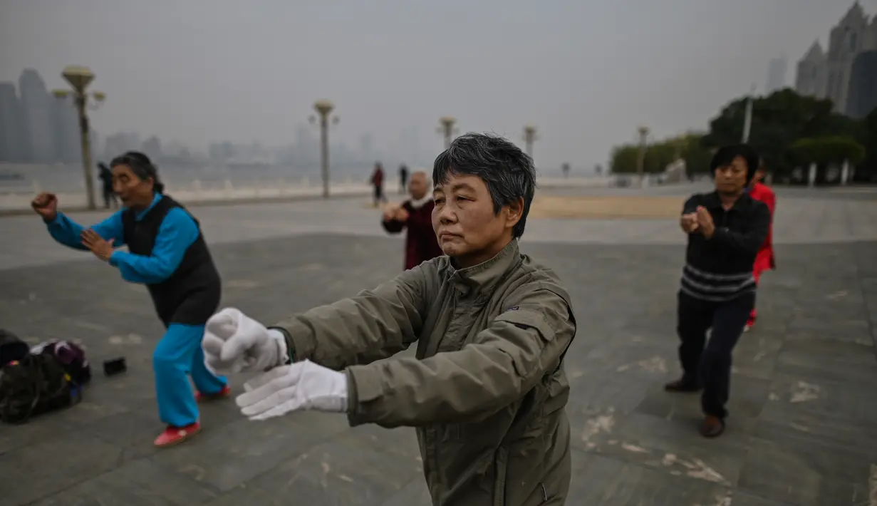 Orang-orang berlatih tai chi di pagi hari di sebelah Sungai Yangtze di Wuhan (20/11/2020). Dari total 50.340 kasus yang positif di Wuhan, 3.869 orang telah meninggal dunia akibat Covid-19 dan yang sembuh 46.471 orang. (AFP/Hector Retamal)
