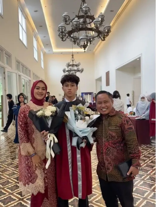 Pelawak Narji hadir bersama sang istri di wisuda putranya mengenakan batik nuansa warna merah. [@diyan_narji]