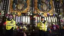 Petugas polisi berdiri di antara karangan bunga yang ditinggalkan di luar Istana Buckingham setelah pengumuman meninggalnya Ratu Elizabeth II, di London, Kamis, 8 September 2022. (Victoria Jones/PA via AP)