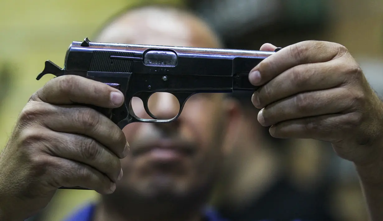 Seorang pria Irak sedang memeriksa pistol di sebuah toko senjata berlisensi di ibu kota Irak, 24 September 2018. Pertama kalinya selama beberapa dekade terakhir, senjata semi otomatis dan pistol dapat dibeli secara legal di Baghdad. (AFP/AHMAD AL-RUBAYE)