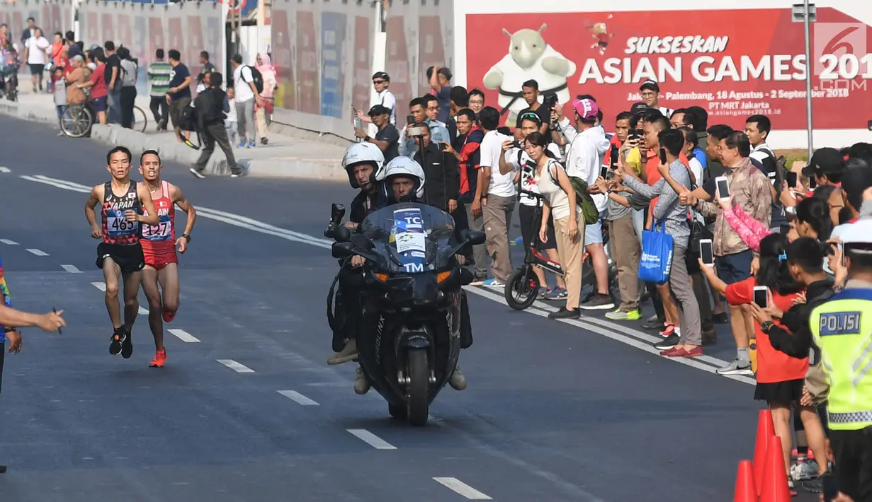 Pelari maraton Jepang, Hiroto Inoue bersaing dengan Elhassan Elabbassi dari Bahrain saat memasuki garis finis lomba Asian Games 2018 di jalan Sudirman, Jakarta, Sabtu (25/8). Hiroto menjadi pemenang lari maraton 42 kilometer. (Merdeka.com/Imam Buhori)