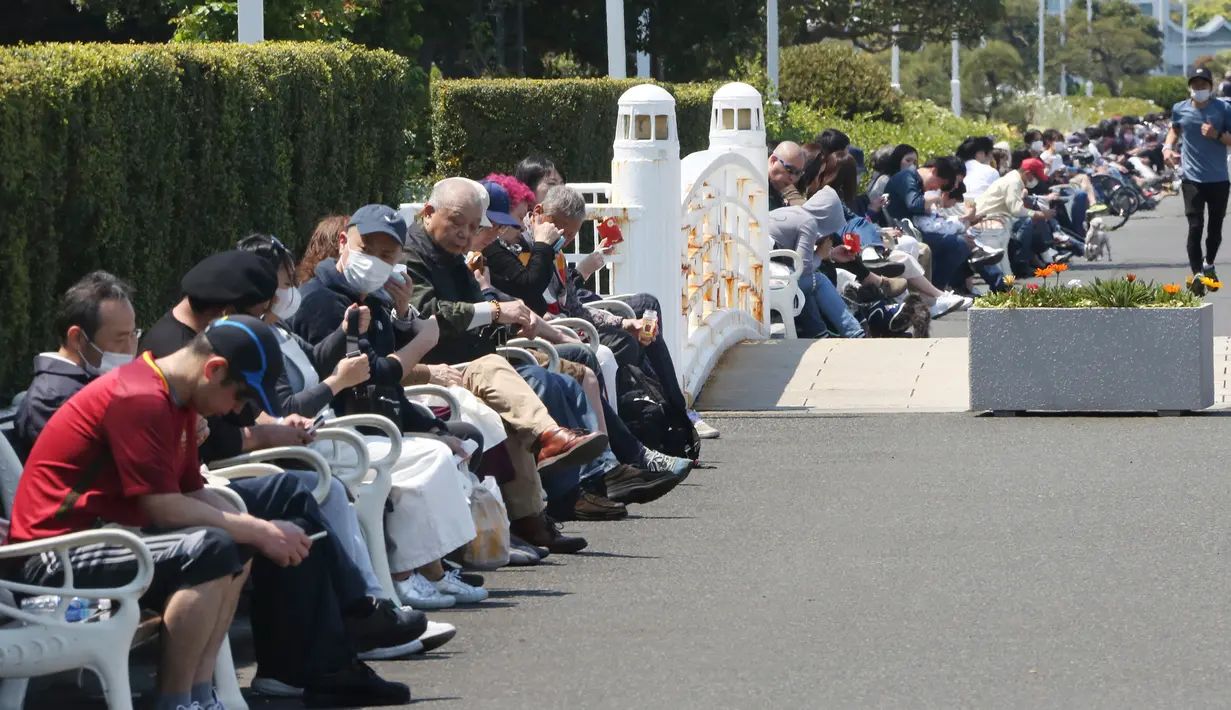 Orang-orang duduk di bangku pada hari libur nasional di sebuah taman di Yokohama, dekat Tokyo, Rabu, (29/4/2020). Warga Jepang menikmati cuaca musim semi yang bagus di taman-taman selama pandemi Covid-19. (AP/Koji Sasahara)