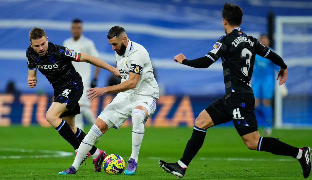 Pemain Real Madrid Karim Benzema (tengah) mengontrol bola antara pemain Real Sociedad Igor Zubeldia (kiri) dan Martin Zubimendi pada pertandingan sepak bola Liga Spanyol di Stadion Santiago Bernabeu, Madrid, 29 Januari 2023. Pertandingan berakhir imbang 0-0. (AP Photo/Manu Fernandez)