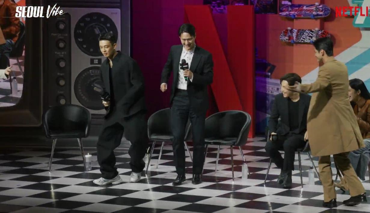 Setelahnya, Yoo Ah In justru kena batunya. Ia juga diminta berjoget seperti sang lawan main. Alhasil, ia pun berjoget sambil tertawa lebar. (Foto: Tangkapan layar YouTube - Netflix).