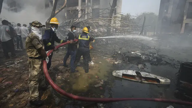 Petugas Pemadam dan Penyelamat Berjbaku di Lokasi Jatuhnya Pesawat Air India