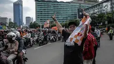 Warga berswafoto dengan latar belakang suporter Persija Jakarta, Jakmania, yang melakukan pawai kemenangan Juara Piala Presiden di kawasan Bundaran HI, Minggu (18/2). Lautan oranye memenuhi jalan-jalan di ibu kota. (Liputan6.com/Faizal Fanani)