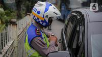 Anggota polisi melakukan penindakan kepada sebuah kendaraan saat ganjil genap di kawasan Jalan D.I Panjaitan, Jakarta, Senin (6/6/2022). Pembatasan mobil dengan sistem pelat nomor ganjil genap di Jakarta diperluas menjadi 25 titik mulai hari ini, Senin, 6 Juni 2022. (Liputan6.com/Faizal Fanani)