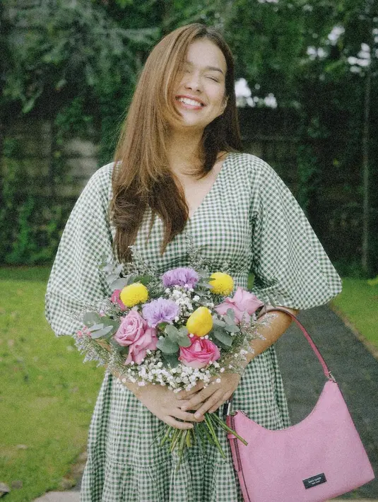 Penampilan girly dari Rebecca Klopper. Manisnya ia ketika mengenakan dress lengan balon kotak-kotak hijau, memegang bunga, dan tas berwarna merah muda yang kontras. Foto: Instagram.