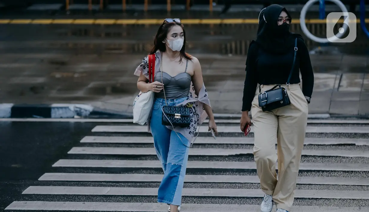 Dua remaja wanita berjalan melintasi zebra cross di Taman Sudirman, Jakarta, Rabu (6/7/2022). Tempat ini viral karena jadi ajang adu fashion anak Citayam, Bekasi hingga Bojong Gede. Mereka mengenakan kemeja flanel oversize, celana model 90-an seperti boot cut atau cutbray, sneakers klasik, dan tentu saja topi. (Liputan6.com/Faizal Fanani)