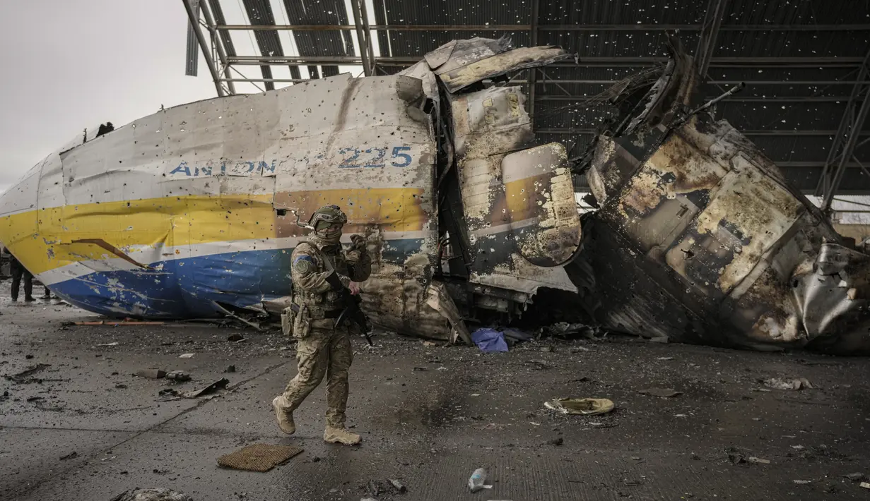 Prajurit Ukraina berjalan di bagian depan pesawat Antonov An-225 Mriya di bandara Antonov di Hostomel, 2 April 2022. Di pintu masuk bandara, pasukan menjaga posisinya, tanda mereka memegang kendali penuh atas landasan pacu yang coba diserbu Rusia di hari-hari pertama perang. (AP Photo/Vadim Ghirda)
