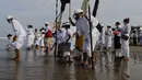 Orang-orang mencelupkan kaki mereka di laut selama ritual Melasti di Bali, Senin (28/2/2022). Ritual yang dilakukan menjelang Hari Raya Nyepi umat Hindu ini diadakan untuk menyucikan alam semesta dari pengaruh buruk, perbuatan dan pikiran buruk. (AP Photo/Firdia Lisnawati)