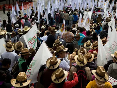 Ribuan petani Meksiko membawa bendera saat melakukan demontrasi terkait North American Free Trade Agreement (NAFTA) di Mexico City (26/7). Mereka menggelar demo mengenai masuknya biji-bijian impor dari AS. (AP Photo / Rebecca Blackwell)