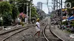 Seorang wanita melintasi rel kereta di kawasan pemukiman padat Pejompongan di tengah pandemi COVID-19, Jakarta, Kamis (28/1/2020). Sensus Penduduk 2020 (SP2020) mencatat penduduk DKI Jakarta pada bulan September 2020 sebanyak 10,56 juta jiwa. (Liputan6.com/Johan Tallo)