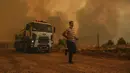 Seorang pria berlari di Desa Sirtkoy yang dilanda kebakaran, dekat Manavgat, Antalya, Turki, Minggu (1/8/2021). Menurut para pejabat, lebih dari 100 kebakaran hutan telah dikendalikan di Turki. (AP Photo)