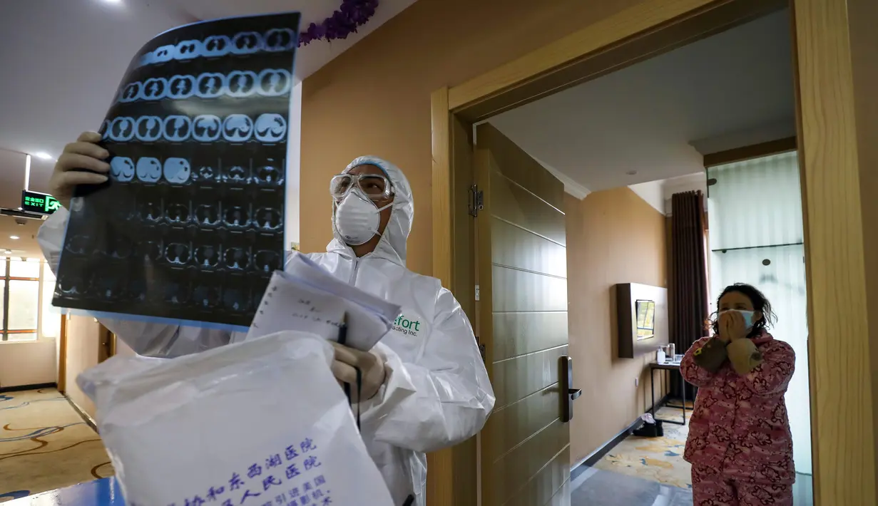 Dokter berpakaian pelindung memeriksa citra medis ketika dia mengunjungi pasien di hotel yang digunakan dalam isolasi medis virus corona di Wuhan, Provinsi Hubei, China, Senin (3/2/2020). Dokter Li Wenliang mengungkapkan penemuannya tentang virus corona kepada teman-temannya. (Chinatopix via AP)