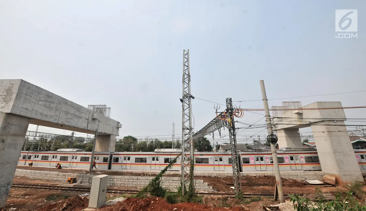KRL melintas di tengah aktivitas pekerja menyelesaikan proyek Double Double Track (DDT) Paket A Stasiun Manggarai-Jatinegara di Manggarai, Jakarta, Selasa (28/8). Proyek DDT Paket A menggunakan Sukuk Negara. (Merdeka.com/Iqbal Nugroho)