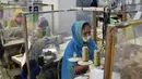 Para buruh bekerja pada stasiun mereka yang dipisahkan oleh sekat sebagai tindakan pencegahan terhadap penularan virus corona COVID-19 di pabrik garmen Civil Engineers Limited, Dhaka, Bangladesh, 17 Agustus 2021. (Munir UZZAMAN/AFP)