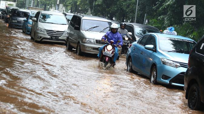 Pengendara motor melintas di antara mobil yang terjebak kemacetan saat banjir di Jalan Lapangan Banteng Utara, Jakarta, Kamis (15/2). Hujan deras yang mengguyur dan buruknya drainase menyebabkan kawasan tersebut banjir (Liputan6.com/Immanuel Antonius)