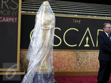 Seorang penjaga keamanan berdiri di samping patung Oscar yang ditutupi plastik pada pintu masuk ke teater Dolby saat persiapan ke-88 Academy Awards di Hollywood, Los Angeles , California, (27/2). (REUTERS / Lucy Nicholson)