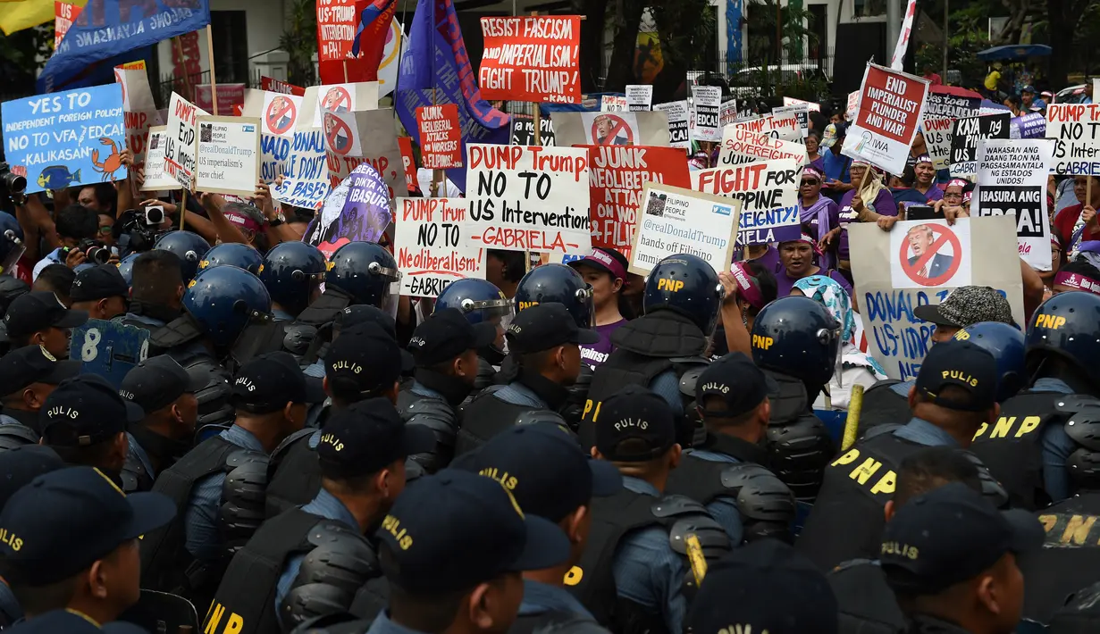 Polisi anti huru-hara berjaga saat unjuk rasa di depan kedutaan AS, Manila, Filipina (20/1). Ratusan warga Filipina berunjuk rasa jelang pelantikan Presiden terpilih AS, Donald Trump. (AFP Photo/Ted Aljibe)