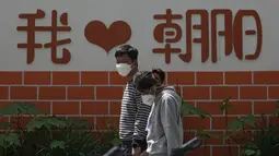 Pejalan kaki yang mengenakan masker berjalan di dekat dinding yang memajang tulisan "I Love Chaoyang" saat akan menjalani tes COVID-19 di distrik Chaoyang, Beijing, Rabu (11/5/2022). Shanghai pada Rabu menegaskan kembali akan mempertahankan pendekatan &ldquo;nol-COVID&rdquo; pengendalian pandemi, sehari setelah kepala Organisasi Kesehatan Dunia (WHO) menyatakan kebijakan itu tidak berkelanjutan dan mendesak China mengubah strategi. (AP Photo/Andy Wong)