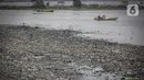 Nelayan melintas di dekat tumpukan sampah laut di muara Kanal Timur di Marunda Kepu, Cilincing, Jakarta, Kamis (8/6/2023). (Liputan6.com/Faizal Fanani)