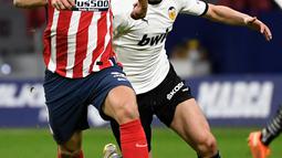 Penyerang Atletico Madrid, Luis Suarez (kiri) bersaing dengan gelandang Valencia, Carlos Soler pada jornada ke-20 Liga Spanyol di Wanda Metropolitano, Senin (25/1/2021) dini hari WIB. Atletico Madrid memetik kemenangan 3-1 atas Valencia. (PIERRE-PHILIPPE MARCOU/AFP)