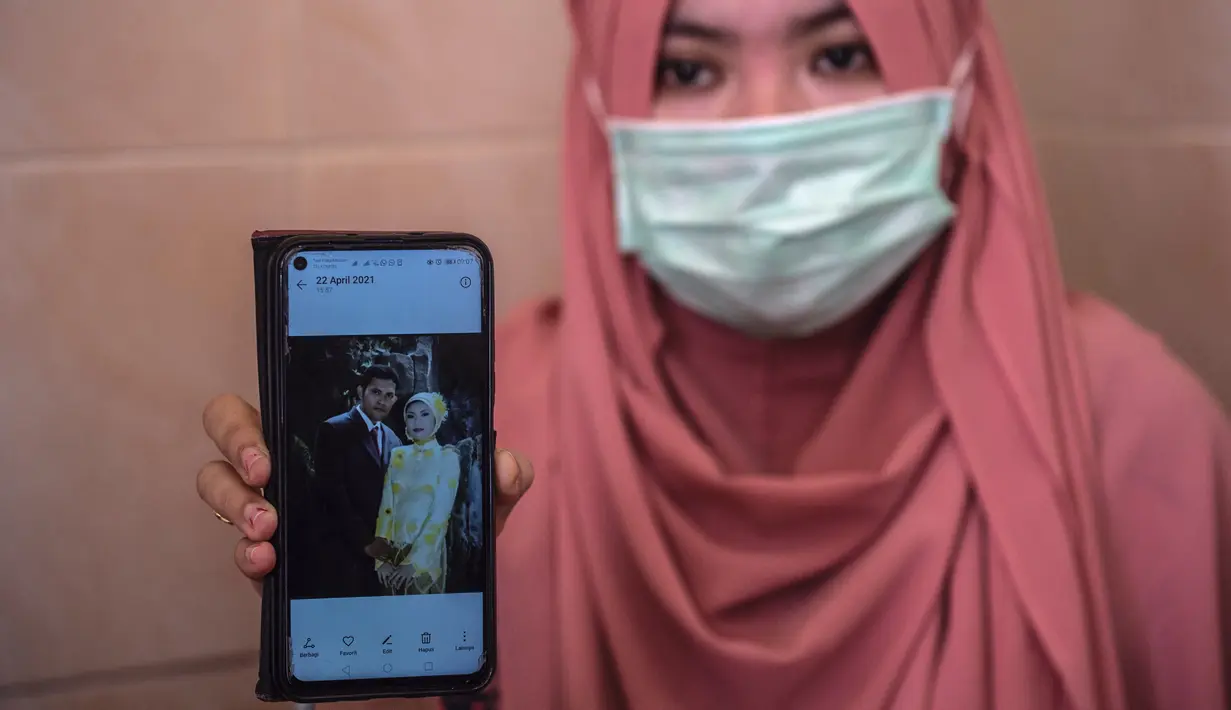Berda Asmara menunjukkan foto pernikahan dengan suaminya Serda Mes Guntur Ari Prasetyo di rumah mereka di Surabaya, Jumat (23/4/2021). Kapal selam KRI Nanggala-402 hilang kontak di perairan utara Pulau Bali saat sedang melaksanakan latihan penembakan dengan torpedo. (Juni Kriswanto/AFP)