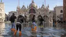 Orang menggunakan jembatan trestle untuk menyeberangi St Mark's Square yang dibanjiri air laut, di Venesia, Italia, Sabtu (4/12/2021). Air mencapai 99 sentimeter di atas permukaan laut dan bagian terendah kota tenggelam. (AP Photo/Luigi Costantini)