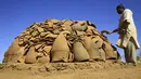 Seorang pekerja Sudan menutupi lubang di oven di bengkel tembikar di Omdourman, di pinggiran barat ibu kota Khartoum (19/1/2022). Para perajin tembikar di Sudan memanfaatkan tanah liat sisa banjir untuk membuat benda-benda kerajinan tersebut. (AFP/Ashraf Shazly)